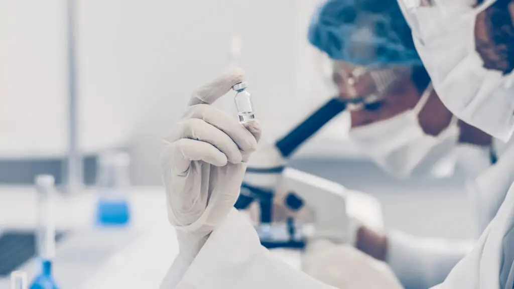 Lab tecg examining a research chemical vial in a laboratory - Lonestar Research, Austin, TX.